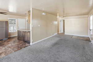 Unfurnished room with dark carpet, ceiling fan, and a textured ceiling