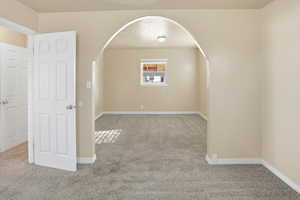 Unfurnished room with arched walkways and carpet flooring