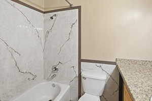 Full bathroom with vanity, shower / tub combination, a wainscoted wall, and tile walls