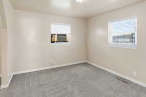 Empty room featuring carpet floors and arched walkways