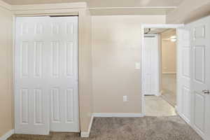 Unfurnished bedroom with light colored carpet and a closet
