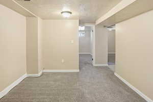 Empty room featuring a textured ceiling and carpet