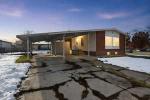 View of front facade featuring an attached carport, driveway, entry steps, and brick siding