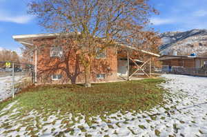 Snow covered back of property with a patio