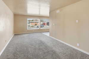 Carpeted empty room featuring a textured ceiling and baseboards