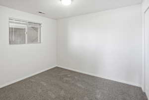 Carpeted spare room featuring baseboards