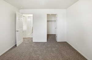 Unfurnished bedroom with a spacious closet and carpet floors