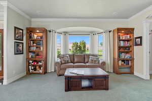 Living room with decorative columns, ornamental molding, and carpet floors