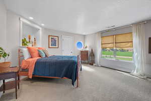 Carpeted bedroom featuring a textured ceiling, recessed lighting, and a baseboard heating unit