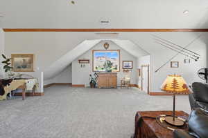 Carpeted living area featuring vaulted ceiling and baseboards