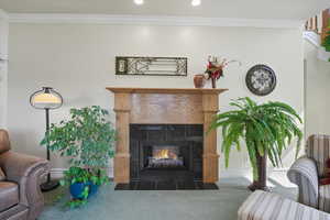 Carpeted living area with ornamental molding, a fireplace, and recessed lighting