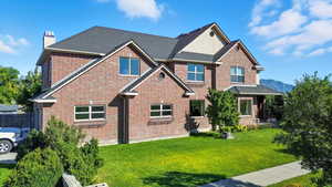 View of front of house with a chimney, a front lawn, brick siding, and a shingled roof