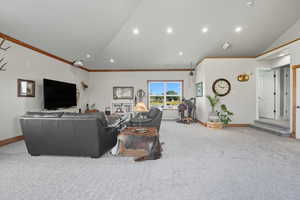 Living room featuring light colored carpet, recessed lighting, ornamental molding, and high vaulted ceiling