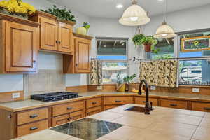 Kitchen featuring brown cabinets, hanging light fixtures, recessed lighting, and black gas stovetop