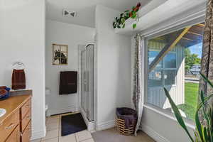 Full bath featuring vanity, a baseboard heating unit, light tile patterned flooring, and a shower stall