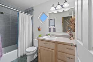 Full bath with shower / tub combo with curtain, vanity, and dark tile patterned floors