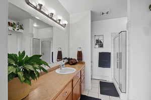 Full bath with light tile patterned floors, vanity, a shower stall, and a baseboard radiator