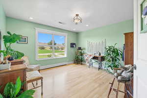 Office area with light wood-style flooring, baseboard heating, a textured ceiling, and recessed lighting