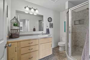 Bathroom with light tile patterned floors, a shower stall, and vanity