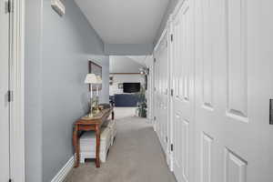 Hallway featuring light colored carpet