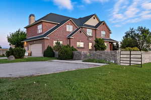 Traditional-style home with brick siding, a chimney, driveway, and a garage
