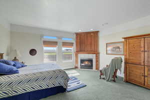 Carpeted bedroom with a tiled fireplace, baseboard heating, and recessed lighting