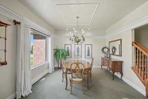 Carpeted dining room with a chandelier and stairs