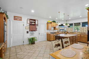 Kitchen with backsplash, light tile patterned floors, hanging light fixtures, recessed lighting, and brown cabinets