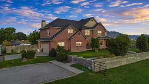 View of front facade featuring concrete driveway, a chimney, brick siding, and an attached garage