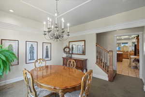 Carpeted dining area with stairs, tile patterned flooring, a chandelier, and recessed lighting
