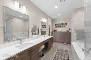 Bathroom featuring double vanity, a garden tub, a marble finish shower, and recessed lighting