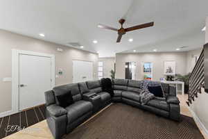 Living room featuring ceiling fan, recessed lighting, a textured ceiling, and stairway