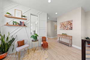 Living area with light wood finished floors and recessed lighting