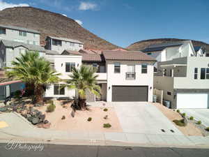 View of front facade with stucco siding, concrete driveway, a mountain view, and a garage