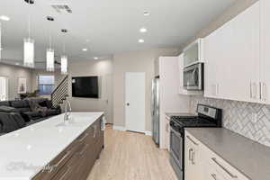 Kitchen featuring stainless steel appliances, open floor plan, pendant lighting, white cabinets, and recessed lighting