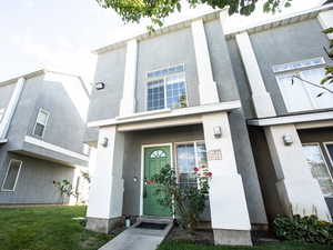 Entrance to property with stucco siding and a yard