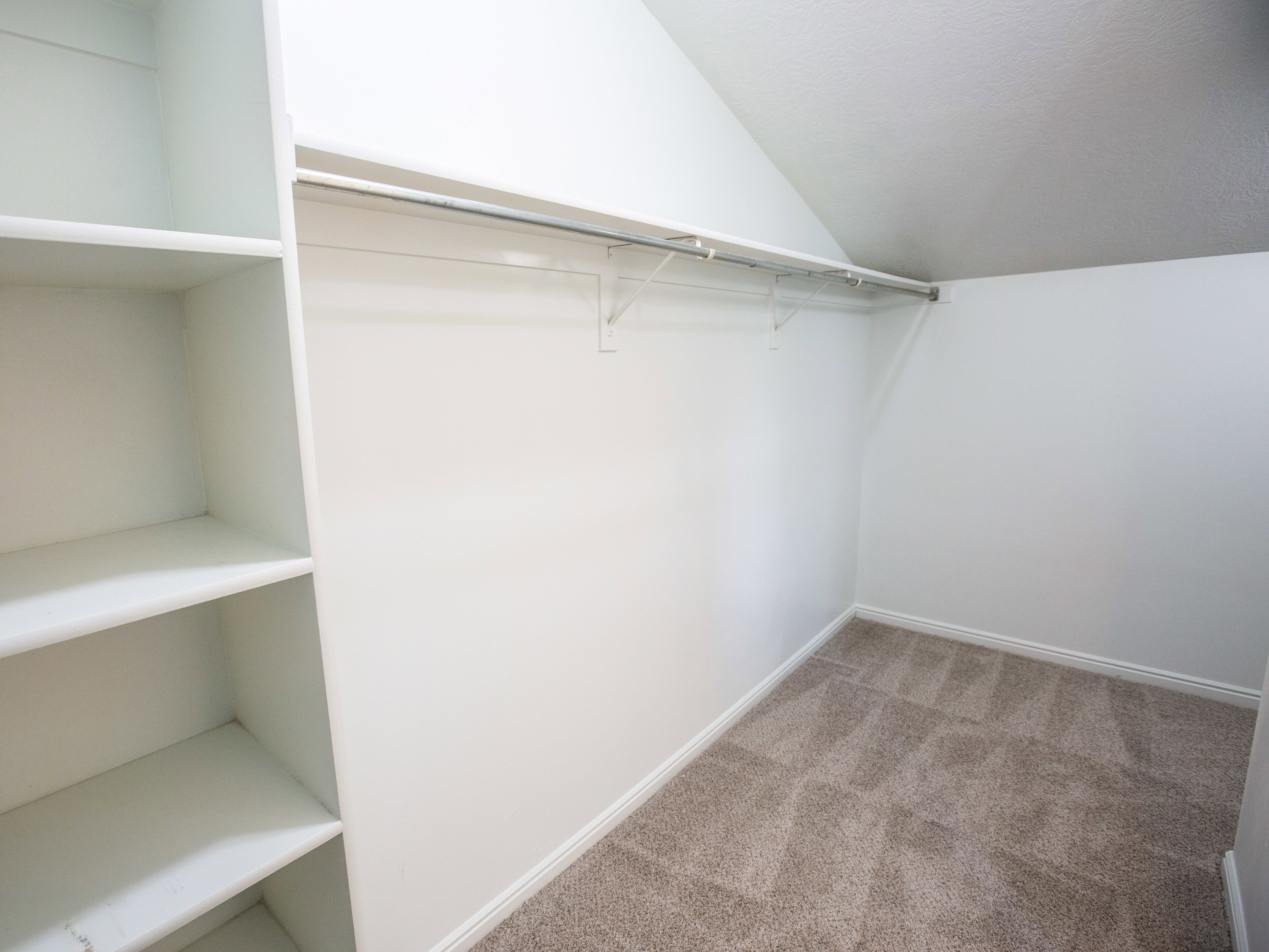 Spacious closet featuring light colored carpet and vaulted ceiling