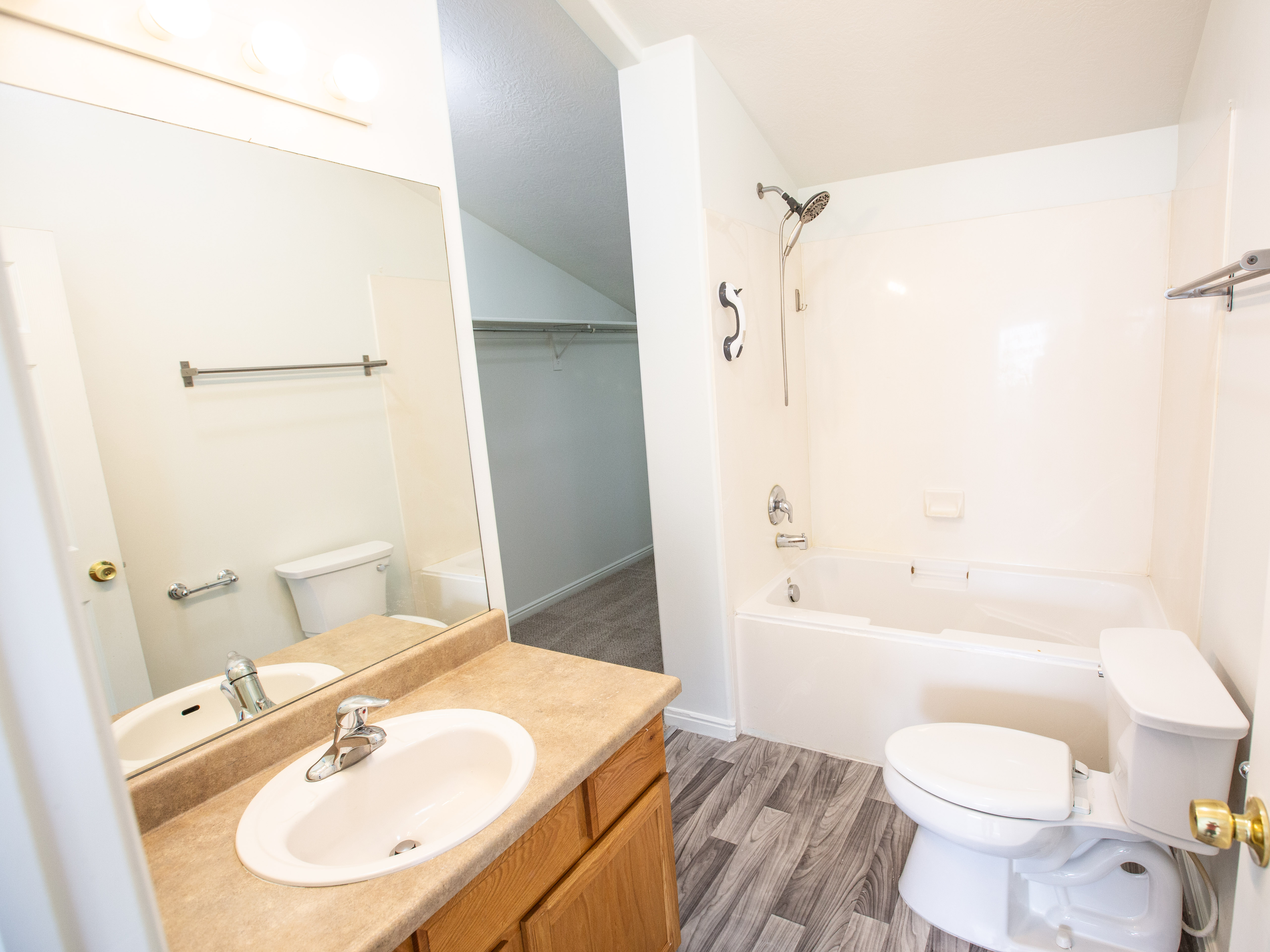 Full bath with bathing tub / shower combination, vanity, and light wood finished floors