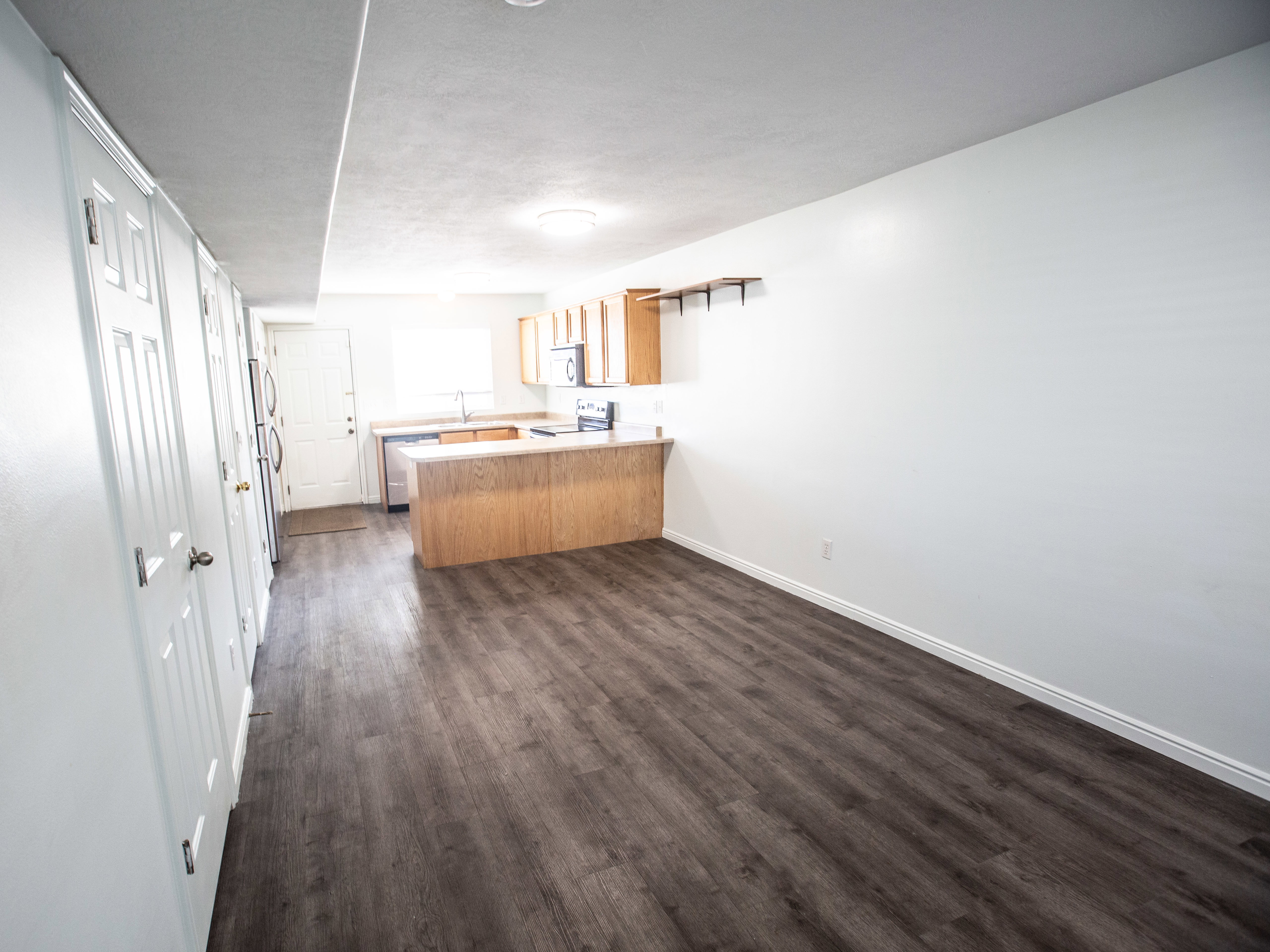 Kitchen with light countertops, a peninsula, dark wood finished floors, appliances with stainless steel finishes, and open floor plan