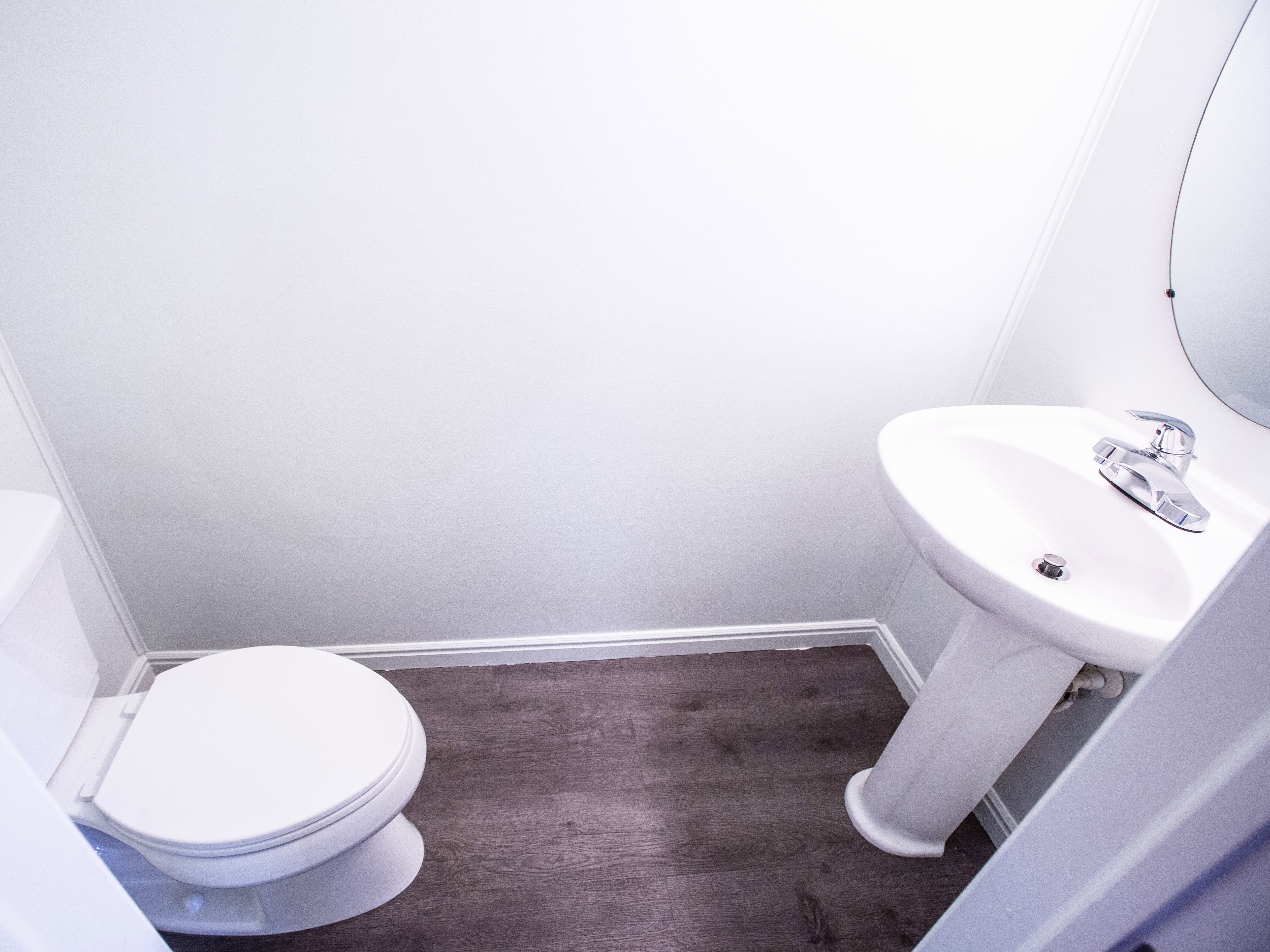 Half bathroom with toilet and dark wood-style floors