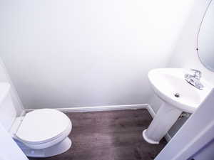 Half bathroom with toilet and dark wood-style floors
