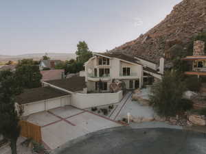 View of front of property featuring driveway, a garage, stucco siding, and a balcony