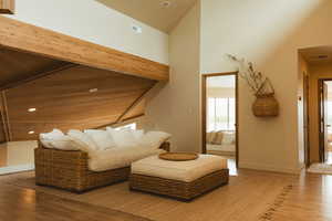 Sitting room with light wood-type flooring, recessed lighting, beam ceiling, and high vaulted ceiling