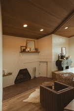 Living room featuring wood finished floors, wood ceiling, recessed lighting, and brick wall