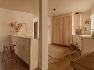 Kitchen with light stone countertops, light wood-style floors, and a breakfast bar