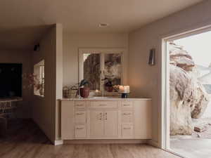 Bar area featuring light wood-type flooring, light brown cabinetry, and light stone countertops