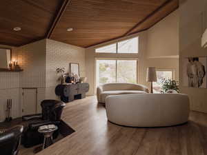 Living room with brick wall, wood finished floors, a wood ceiling with exposed beams, and high vaulted ceiling