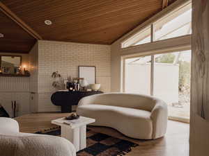 Sitting room featuring brick wall, lofted ceiling, wooden ceiling, and wood finished floors
