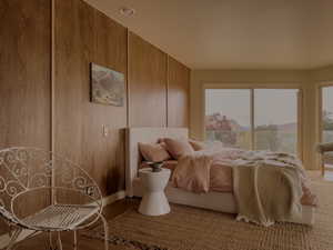 Bedroom with wood finished floors and wood walls