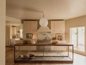 Kitchen with light wood-type flooring, a kitchen island, and pendant lighting